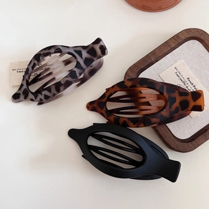 Three assorted leopard print and matte black banana hair clips on a white background