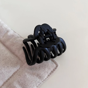 Detail view of small matte black hair claw clip with interlocking teeth for half-up hairstyles