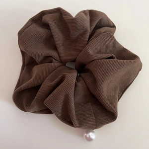 Deep brown corduroy hair scrunchie with pearl pendant accessory on a beige background