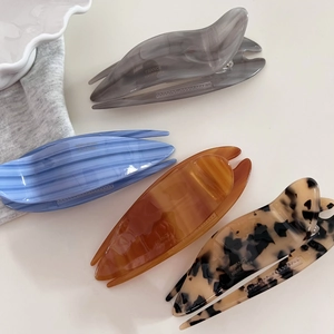 Detail view of four acetate hair clips with marble, amber and tortoiseshell patterns