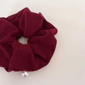 Macro shot of burgundy corduroy hair scrunchie with elegant white pearl pendant detail