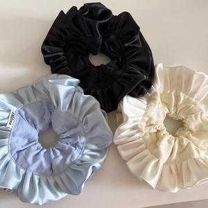 Detailed macro view of large satin scrunchies with elegant double-layered pleated ruffles