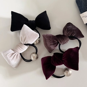 Detail of four velvet bow hair ties in black, white, brown and wine red with metallic beads