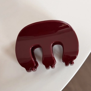 Vue détaillée de la pince à cheveux brillante bordeaux en résine avec design en forme de M