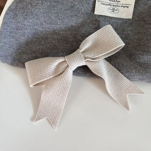 Gros plan sur la barrette à nœud en tricot blanc cassé montrant la texture côtelée douce