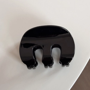 Gros plan d'une pince à cheveux noire brillante en forme de M avec une finition polie