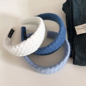 Detailed close-up of three knitted headbands in blue and white with handmade labels