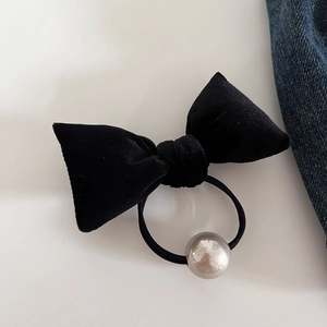 Detail of vintage black velvet bow hair tie with silver bead on blue denim background