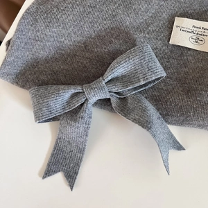 Détail d'une pince à cheveux en tricot gris avec nœud et étiquette en tissu style français