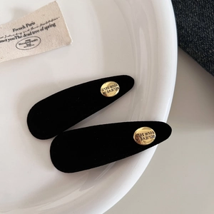 Makroaufnahme schwarzer beflockter Haarklammern mit gravierten goldenen Metallelementen