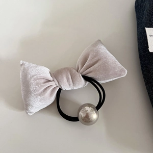 Detailed view of light gray velvet bow hair tie with silver bead on a white background