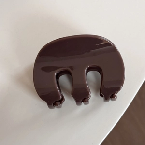 Gros plan d'une pince à cheveux marron foncé brillante en matériau PC épais pour chignons