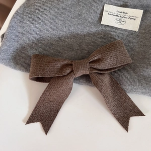 Gros plan détaillé d'un bonnet en tricot gris avec un grand nœud marron et une étiquette en tissu