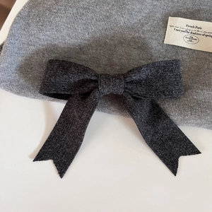 Détail de la maille et du nœud en laine gris foncé de ce bonnet d'hiver douillet