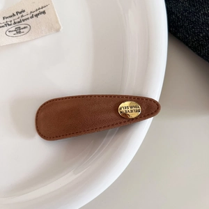 Nahaufnahme einer braunen Wildleder-Haarspange mit goldener Schnalle und Gravur-Details