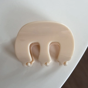 Détail d'une pince à cheveux beige brillante en forme de M en résine PC durable