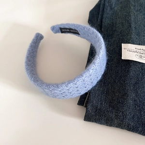 Detailed view of light blue knitted headband with texture and handmade label tag