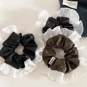 Détail de chouchous plissés en cuir et organza avec étiquettes faites à la main