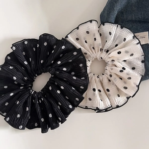 Close-up of black and white polka dot chiffon scrunchies with pleated texture and elastic