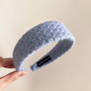 Close-up of blue knitted headband with soft fuzzy texture and Hand Made fabric label