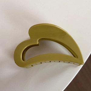 Détail de la pince à cheveux cœur vert olive avec finition brillante et prise sûre