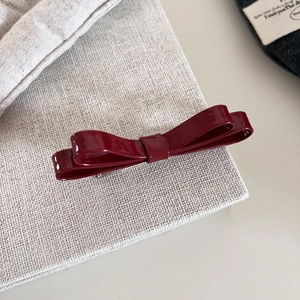 Elegant wine red patent leather double bow hair clip with glossy finish on fabric background