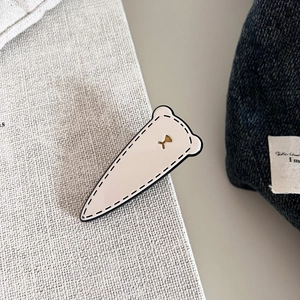 Vintage cream bear hair clip with black stitching and gold metal bear accent on fabric