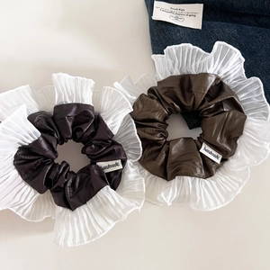 Détail d'un chouchou en cuir et mousseline avec étiquette fait main et plis fins