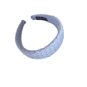 Light blue knitted padded headband with a minimalist woven texture and handmade tag