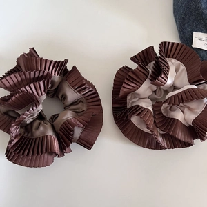Close-up of brown pleated satin scrunchies with elegant glossy texture and double layers