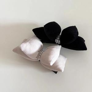 Detail of velvet bow hair clips with pearls in classic black and cream white colors