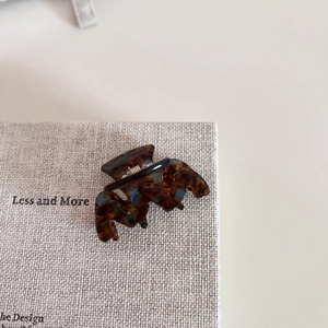 Detail view showing tortoise shell texture and metal spring on acetate claw hair clip