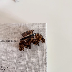 Detail of tortoise shell acetate hair claw clip with golden spring on woven texture