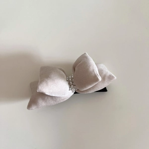 Macro shot of elegant grey velvet bow hair clip with decorative pearl rows on top