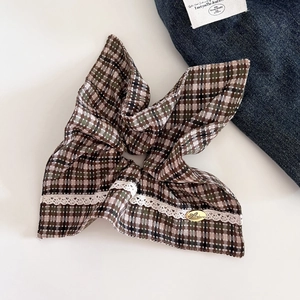 Detail of checkered hair scrunchie with white lace trim and gold butterfly metal charm