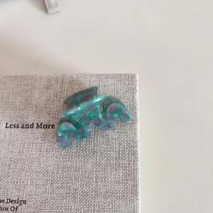 Detailed macro view of acetate M-shaped hair claw with green and purple marble patterns