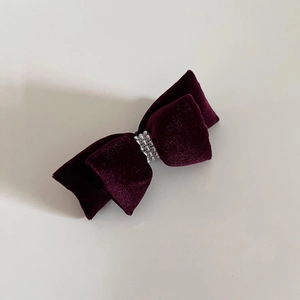 Detail view of deep purple velvet bow hair clip with three rows of silver pearls