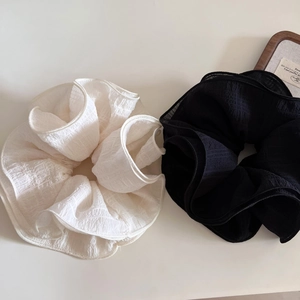 Close-up of set of 2 large ruffled fabric hair scrunchies in cream white and black colors