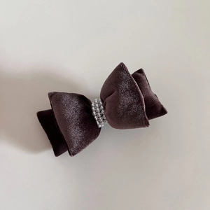 Close-up of velvet bow hair clip with elegant pearl detailing and rich texture