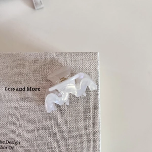 Close-up of small M-shaped acetate hair claw clip with pearlescent white finish
