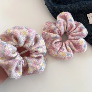 Detail of plush floral scrunchies showing soft pink yellow and blue knit texture