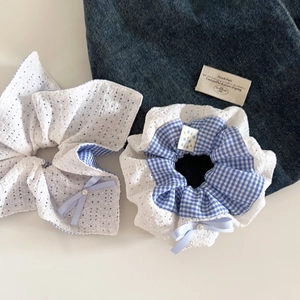 Détail du chouchou à carreaux bleus avec broderie dentelle et perle sur fond en denim