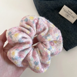 Detail of plush pink floral scrunchie featuring soft faux fur texture and pastel patterns