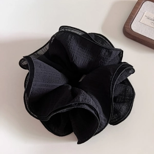 Detailed macro view of large layered black scrunchie with pleated texture and lace edge