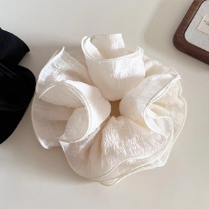 Detailed view of large white pleated hair scrunchie with soft ruffled fabric texture
