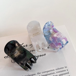 Three elegant acetate hair claws in dark green, pearl white, and blue-purple marble textures