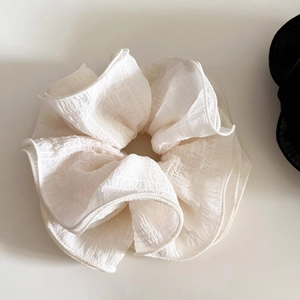 Detail view of the elegant white oversized scrunchie with soft pleated lace texture