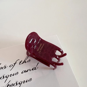 Close-up of burgundy acetate hair claw with tortoiseshell pattern and gold text detail