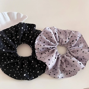 Vue détaillée de grands chouchous en satin à pois en noir et violet lavande