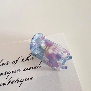 Detail view of acetate hair claw clip with blue marble pattern and gold Barrette La France text